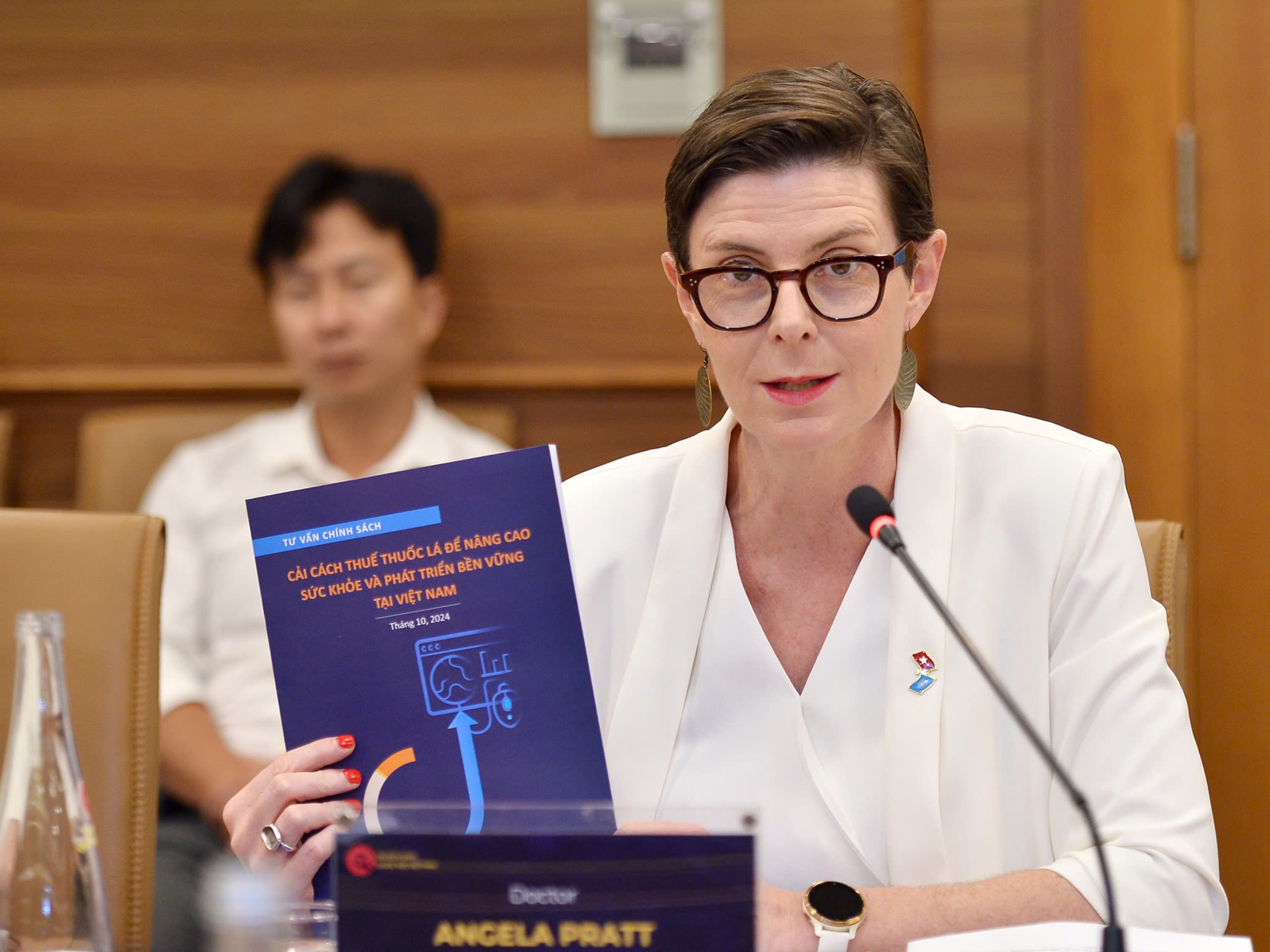 Dr Angela Pratt holding the policy brief "Tobacco Taxation to Advance Health and Sustainable Development in Viet Nam"